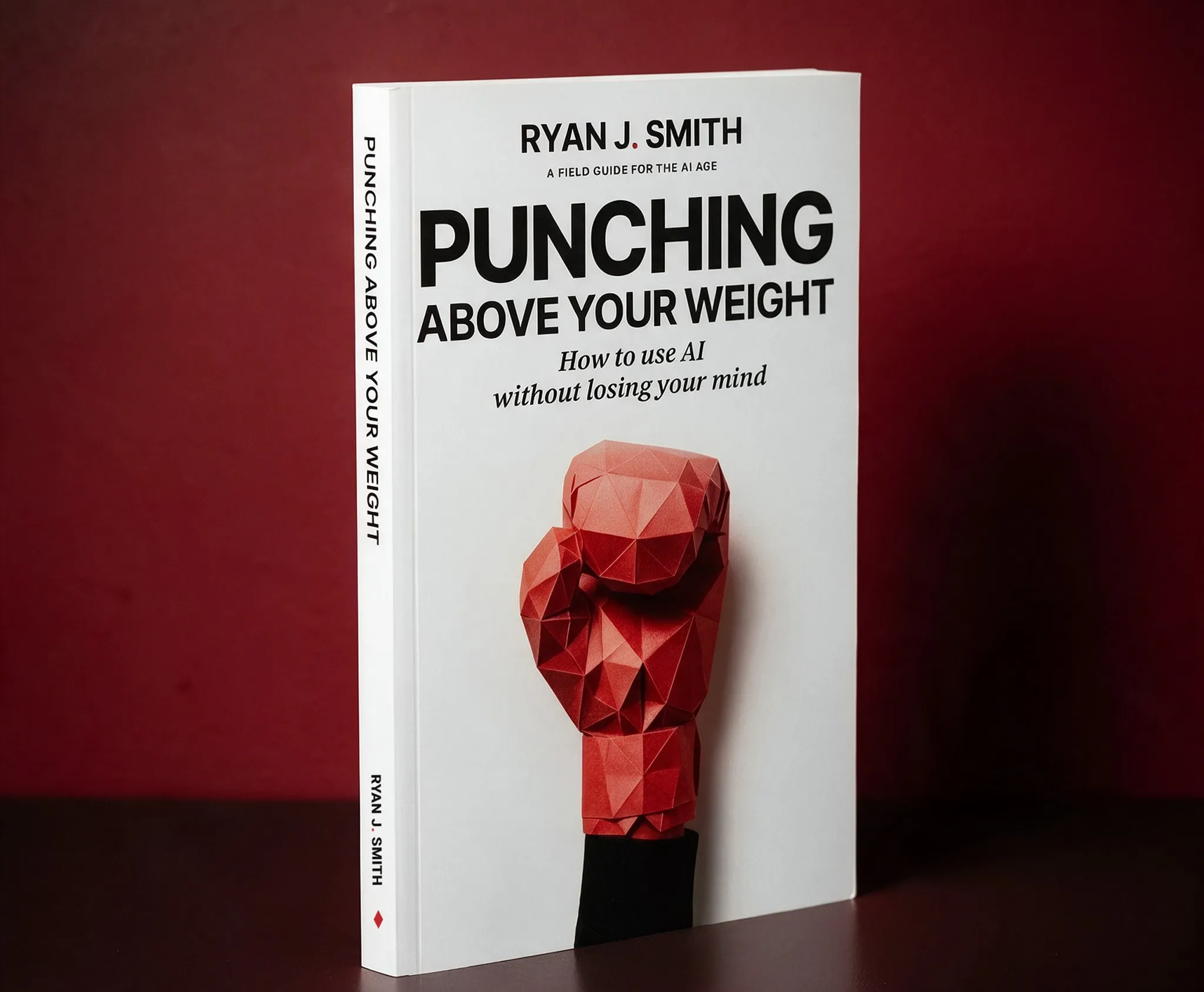 The Punching Above Your Weight paperback standing against a deep red wall, a red paper boxing glove raised on its cover
